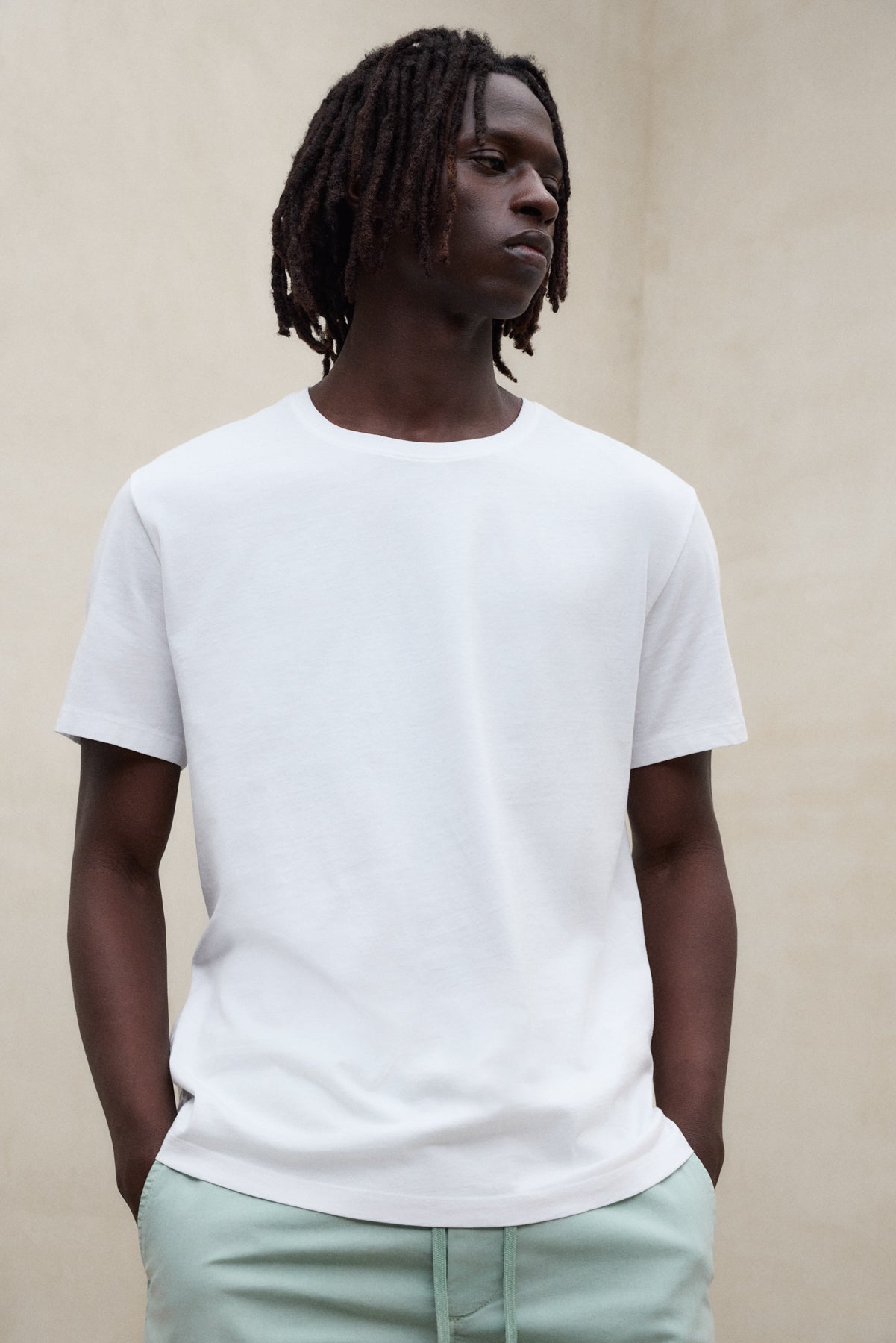 Camiseta blanca básica para hombre de la marca ecoalf.probinada con pantalón verde claro de fibras sostenibles.