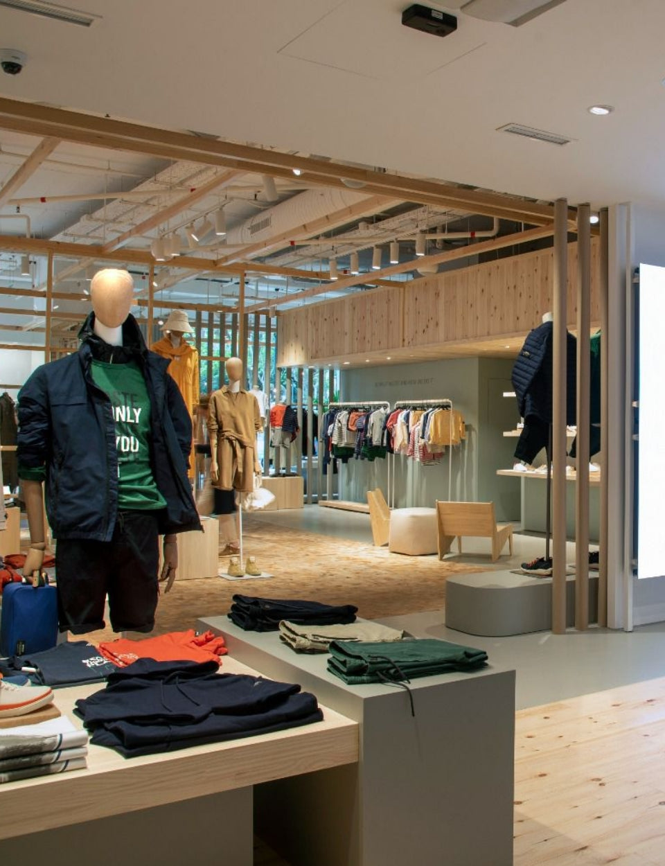 Espacio de la marca Ecoalf con maniquíes vestidos con ropa sostenible y una gran pantalla mostrando un mensaje ambiental.